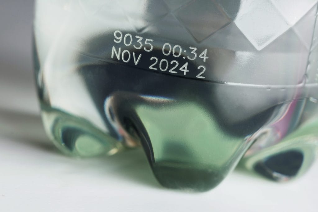Close-up of a transparent PET bottle with laser marked production code and date