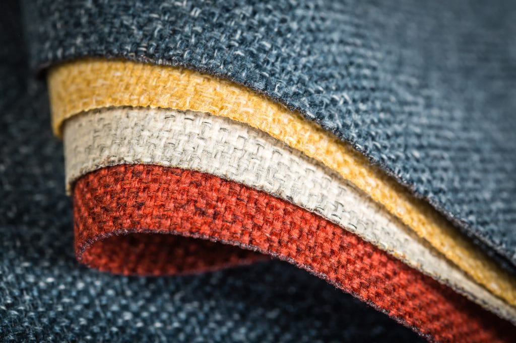 Close-up of several layers of fabric rolled together, showing red, yellow, white and blue textiles stacked