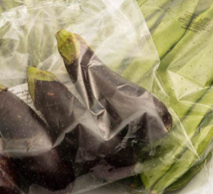 Aubergines and green beans packaged in transparent perforated plastic film