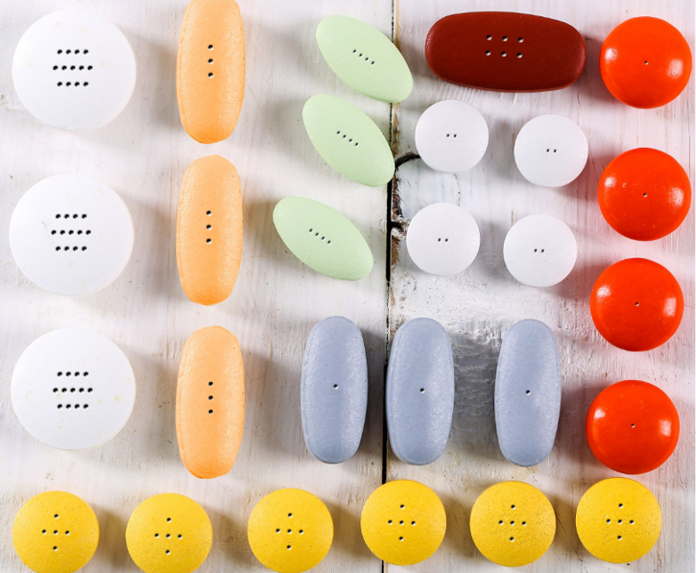 Assorted colourful tablets and capsules of various shapes and sizes with precision CO2 laser-drilled holes