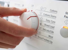 Plastic marking Detail of a person switching washing programs on the control panel