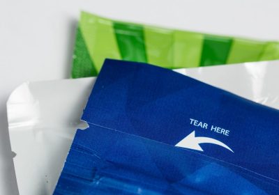 Easy-tear laser scribing on paper sachet Close-up of a blue packaging pouch with a straight laser scribed tear line and “TEAR HERE” arrow